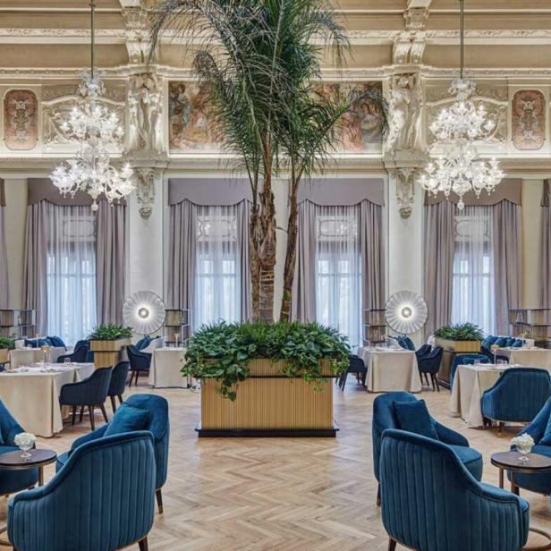 Ein elegantes Restaurant mit hohen Decken, Kristalllüstern und blauen Samtsesseln.