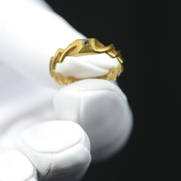 Ein goldener Ring wird von einer Hand mit weißem Handschuh gehalten.