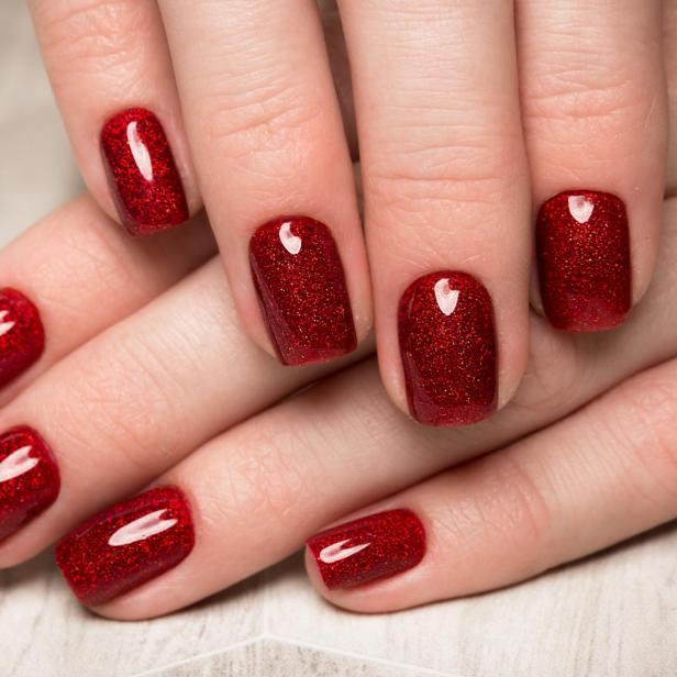 Nahaufnahme von Händen mit rot glitzerndem Nagellack.