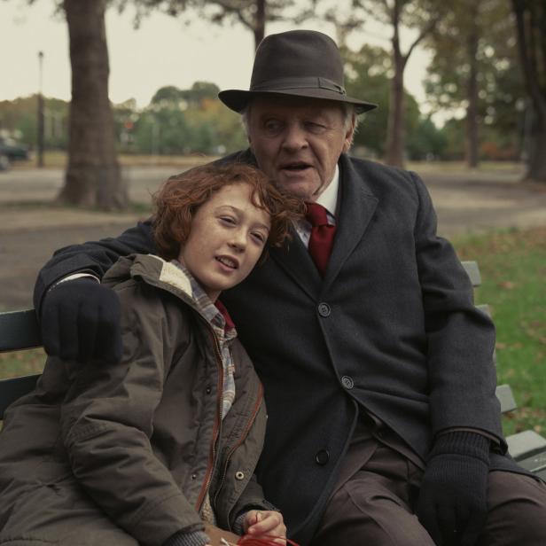 Anthony Hopkins sitzt mit einem Kind auf einer Parkbank.