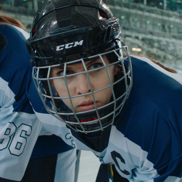 Nahaufnahme von drei jungen Eishockeyspielerinnen mit Helmen und Trikots.
