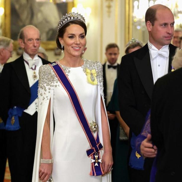 Prinzessin Kate in einem weißen Kleid mit Tiara und Schärpe bei einem formellen Anlass.