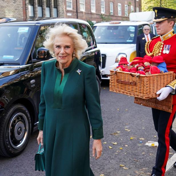 Königsgemahlin Camilla neben einem Soldaten mit einer Kiste Paddington-Bären.