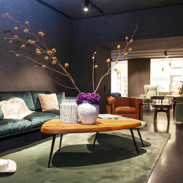 Ein Wohnzimmer mit einem grünen Sofa, einem Holztisch und Blumenarrangements.