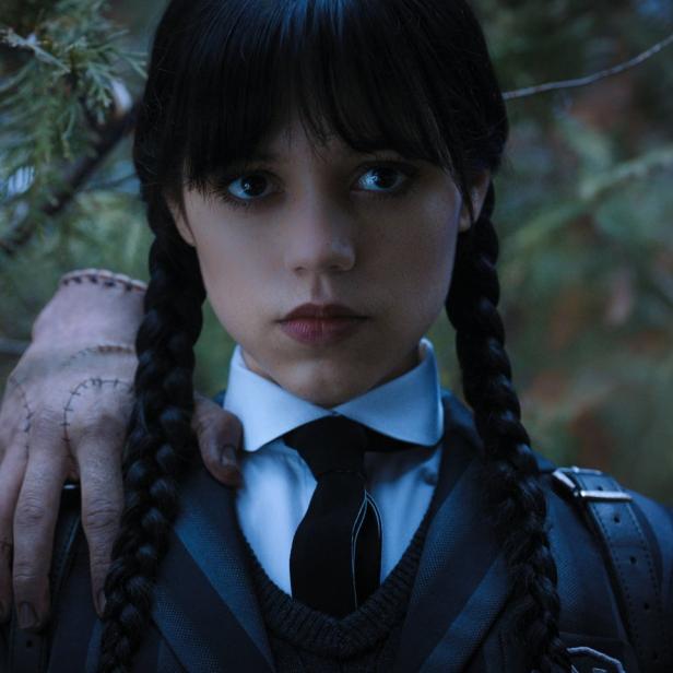 Jenna Ortega als Wednesday Addams mit „Things“ Hand auf ihrer Schulter.