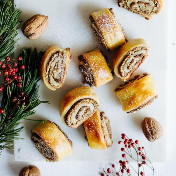 Mehrere Stücke Nussstrudel liegen auf einem Brett, dekoriert mit Tannenzweigen und Nüssen.