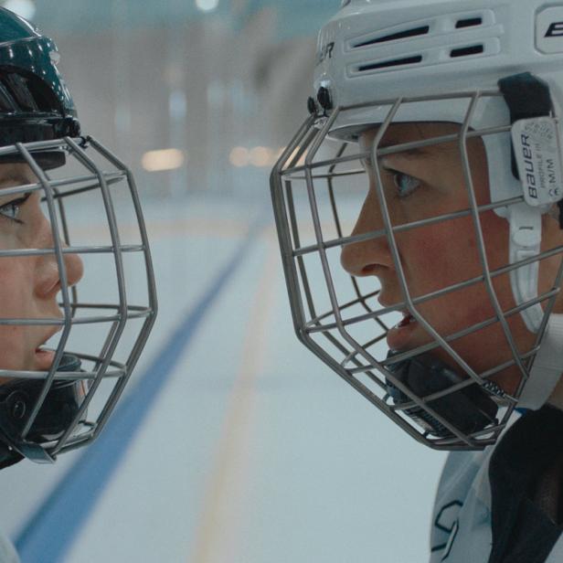 Zwei Eishockeyspielerinnen stehen sich mit Helmen und Visieren gegenüber.