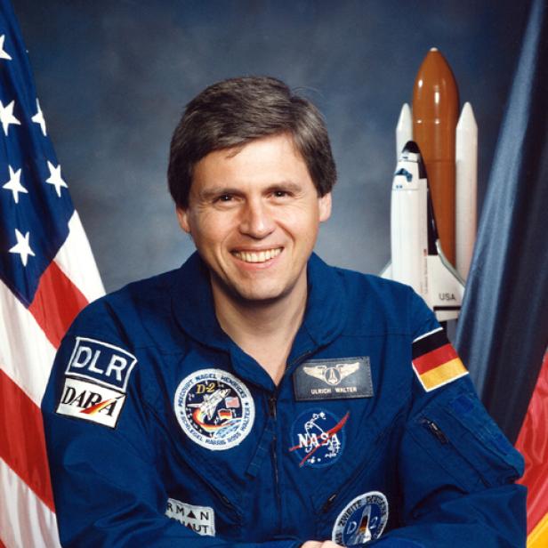 Ein Porträt des deutschen Astronauten Ulrich Walter in seiner blauen NASA-Raumfahreruniform.