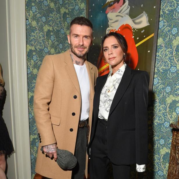 David und Victoria Beckham posieren vor einer gemusterten Tapete.