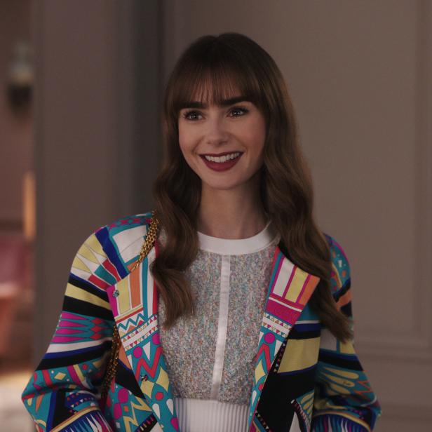 Lily Collins lächelt in einem bunten Blazer.