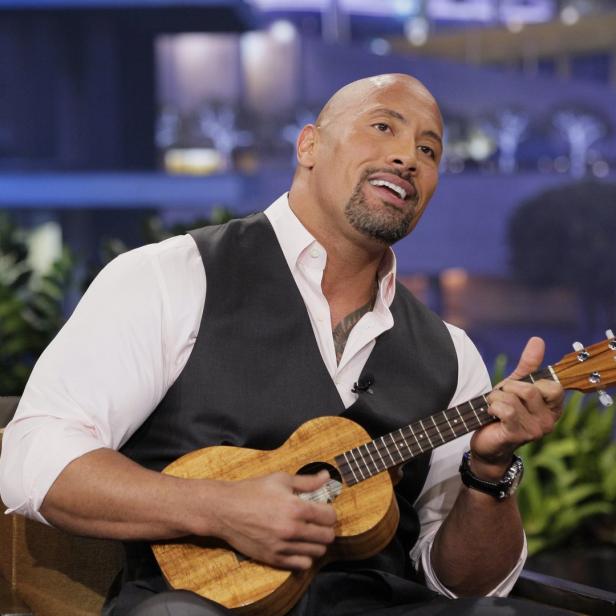 Dwayne „The Rock“ Johnson spielt Ukulele in einem Fernsehstudio.