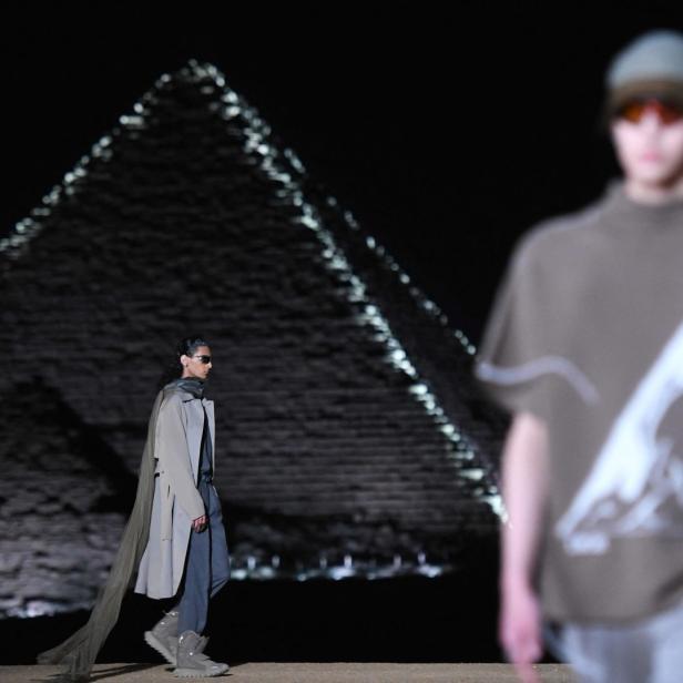 Ein Model läuft vor einer Pyramide bei einer Modenschau.