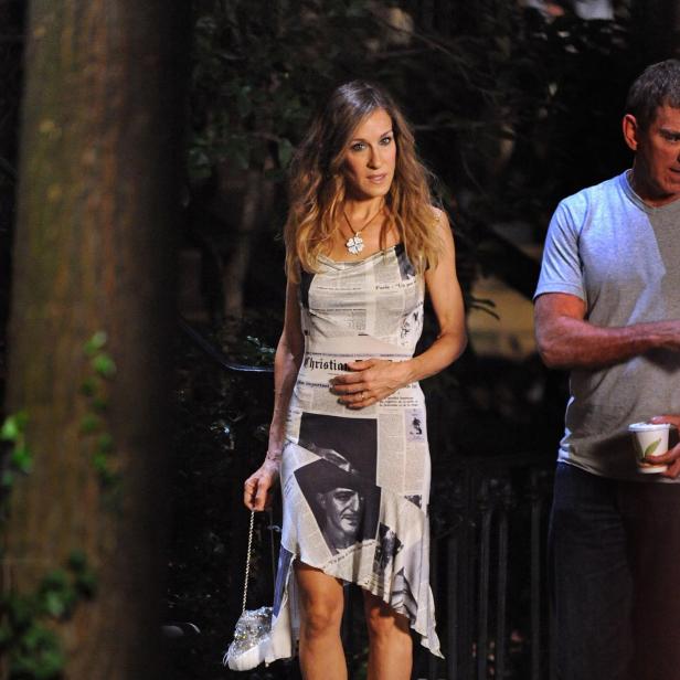 Sarah Jessica Parker in einem Kleid mit Zeitungsmuster auf einer Treppe.