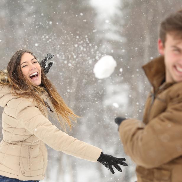 Ein Mann und eine Frau werfen sich im Schnee Schneebälle zu.