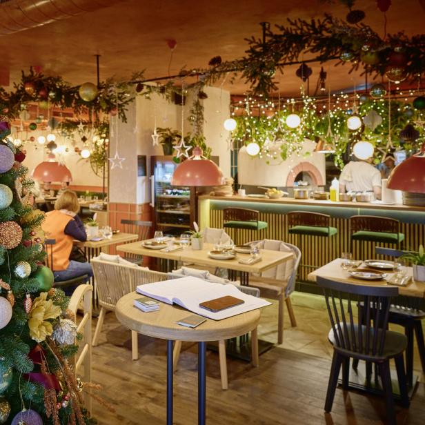 Ein geschmückter Weihnachtsbaum steht in einem festlich dekorierten Restaurant.