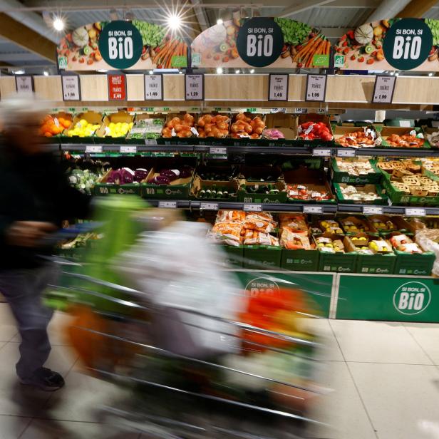 Ein Kunde schiebt einen Einkaufswagen durch die Gemüseabteilung eines Supermarktes.