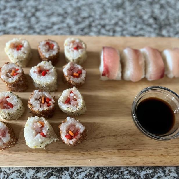 Sushi-Rollen und Nigiri mit Sojasauce auf einem Holzbrett.