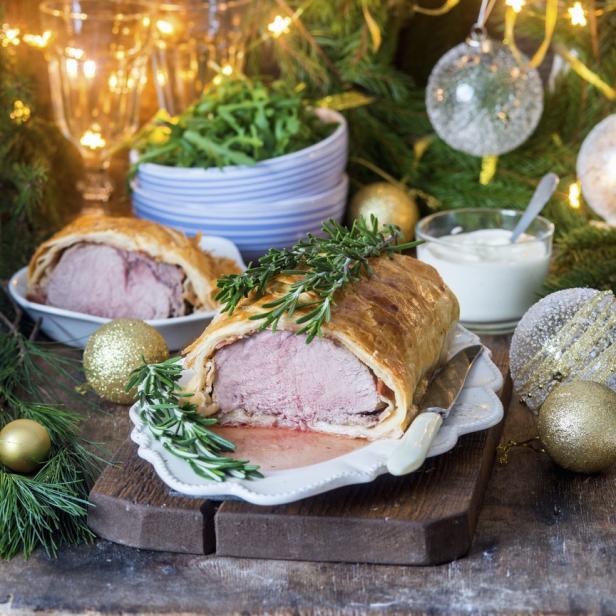 Ein festliches Gericht, möglicherweise Schweinefilet im Blätterteig, mit Beilagen und Weihnachtsdekoration.