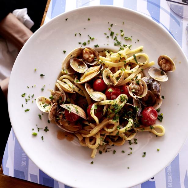 Ein Teller Linguine mit Venusmuscheln, Tomaten und Petersilie.