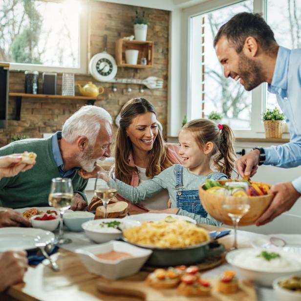 Eine Familie sitzt zusammen am Esstisch und genießt eine Mahlzeit.