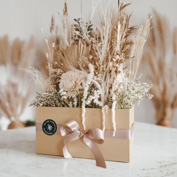 Ein Arrangement aus Trockenblumen in einer beigen Schachtel mit Schleife.