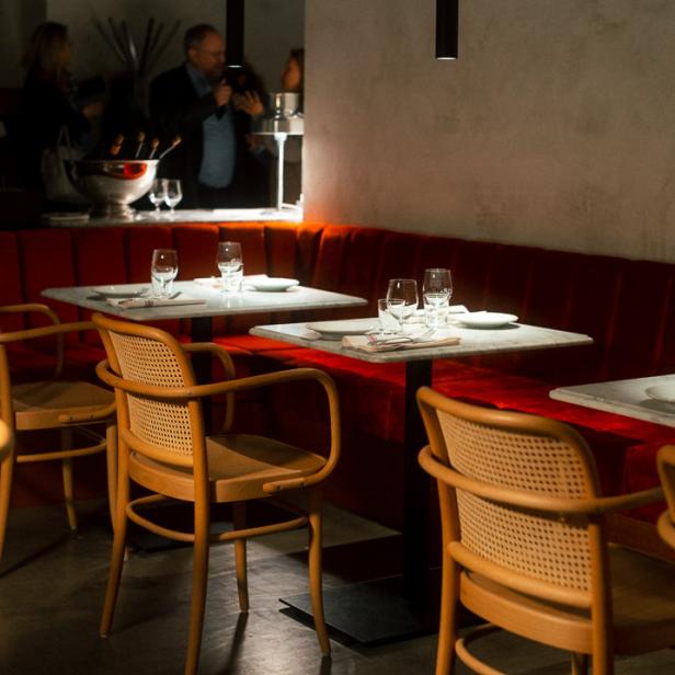 Ein Restaurant mit gedeckten Tischen und roter Sitzbank.