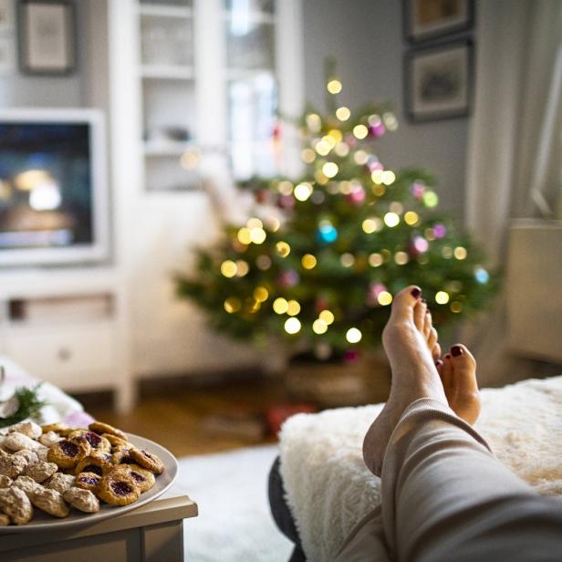 Ein Teller mit Keksen, eine Tasse Kaffee und ein Weihnachtsbaum im Hintergrund.