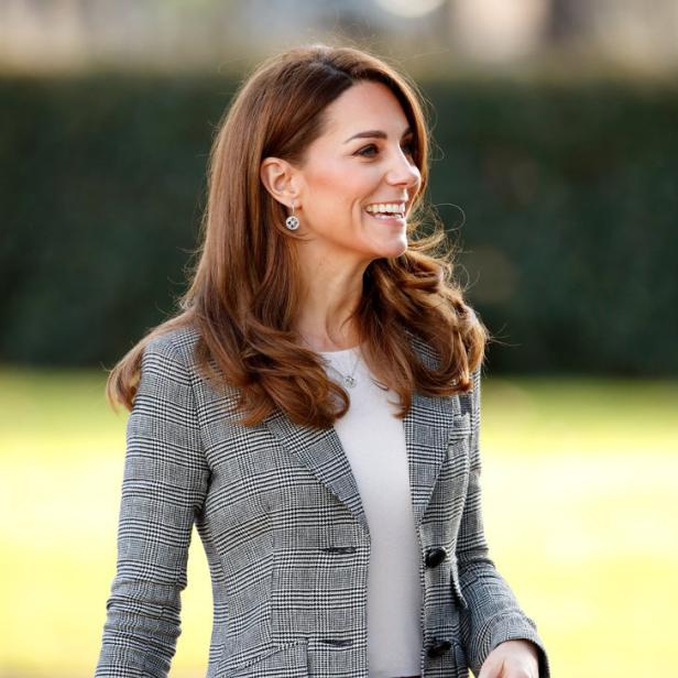 Catherine, Prinzessin von Wales, lächelt in einem karierten Blazer und einer roten Hose.