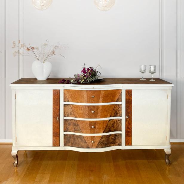 Ein restauriertes Sideboard mit drei Schubladen und dekorativen Elementen steht in einem hellen Raum.