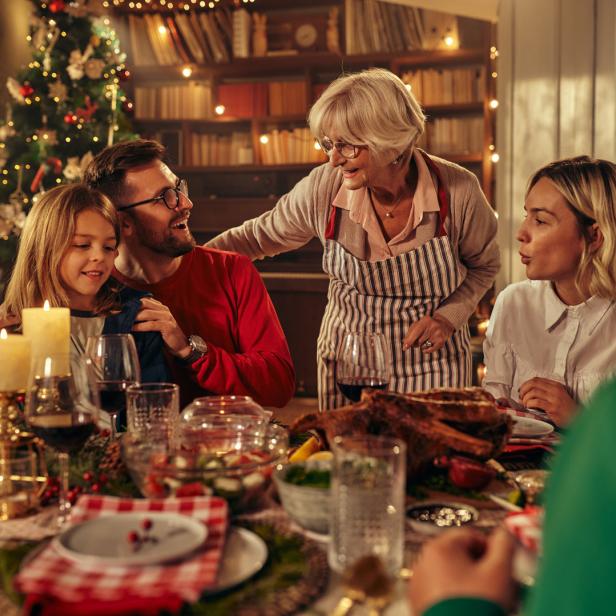 Eine Familie feiert Weihnachten und sitzt am Esstisch.