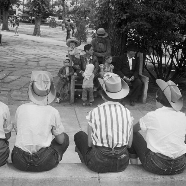 Eine Gruppe von Menschen mit Cowboyhüten sitzt im Park.