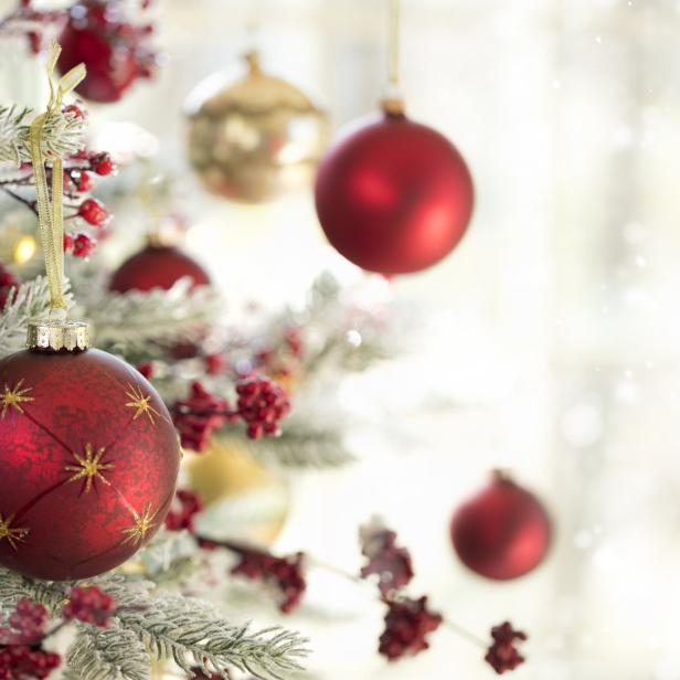 Ein Weihnachtsbaum ist mit roten und goldenen Kugeln geschmückt.