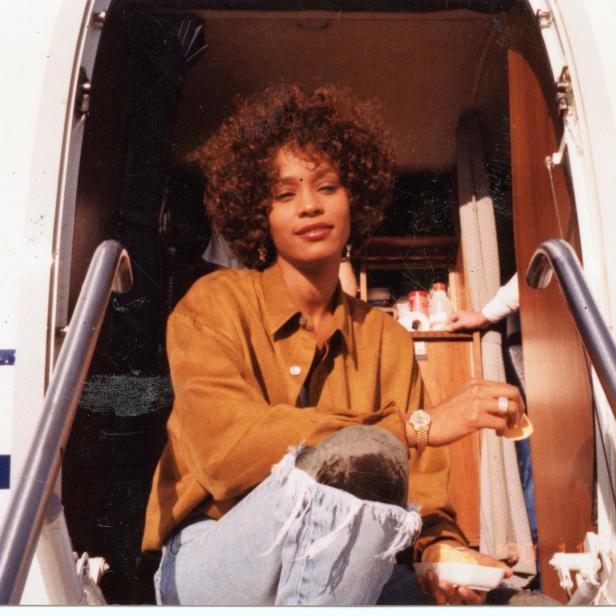 Whitney Houston sitzt auf der Treppe eines Privatjets.