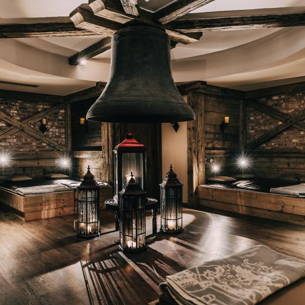 Ein Ruheraum mit Holzböden, Betten und einer großen Glocke an der Decke.