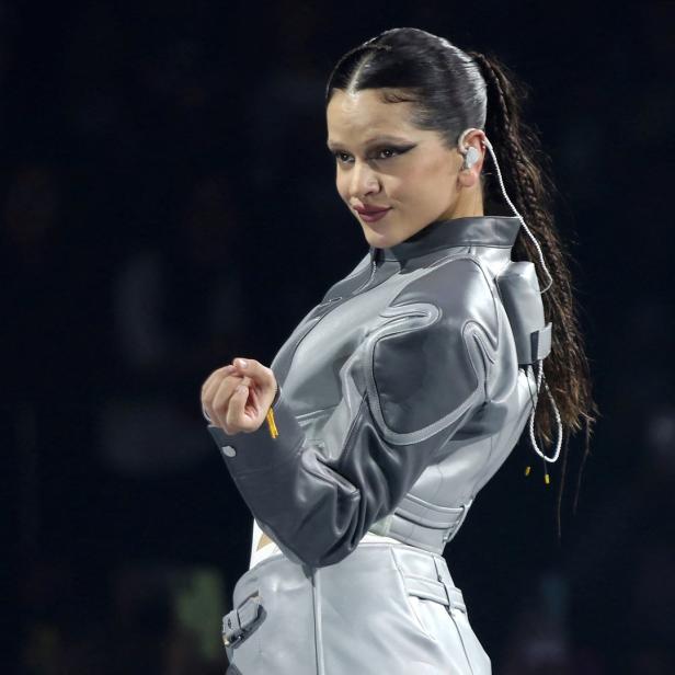 Rosalía trägt eine futuristisch anmutende, grau-silberne Jacke und blickt über ihre Schulter.