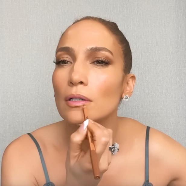 Jennifer Lopez trägt Lippenstift auf.