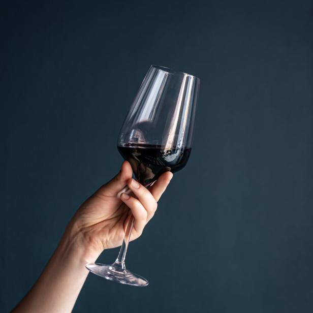Eine Hand hält ein Glas Rotwein.