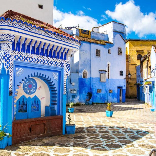 Eine blau gestrichene Straße mit einem verzierten Brunnen in Chefchaouen, Marokko.