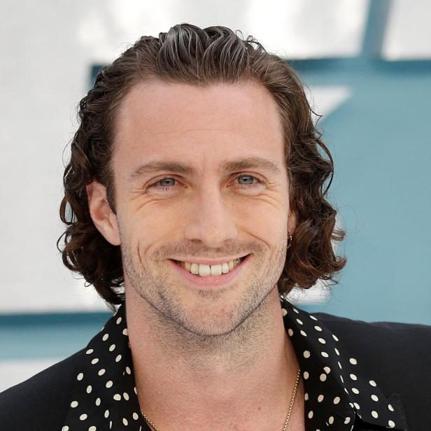 Porträt von Aaron Taylor-Johnson, der in die Kamera lächelt.
