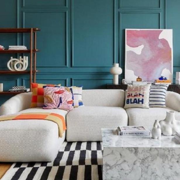 Ein Wohnzimmer mit einem weißen Sofa, einem Marmortisch und einem schwarz-weiß gestreiften Teppich.