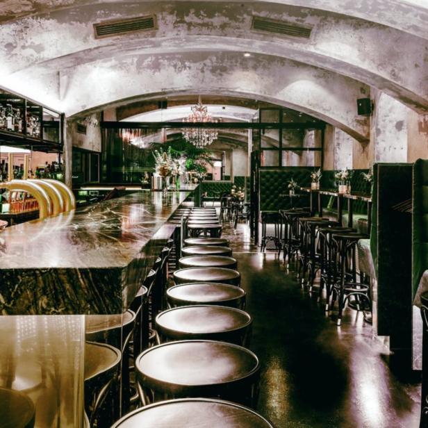 Innenansicht einer Bar mit dunklen Möbeln und einer langen Theke.