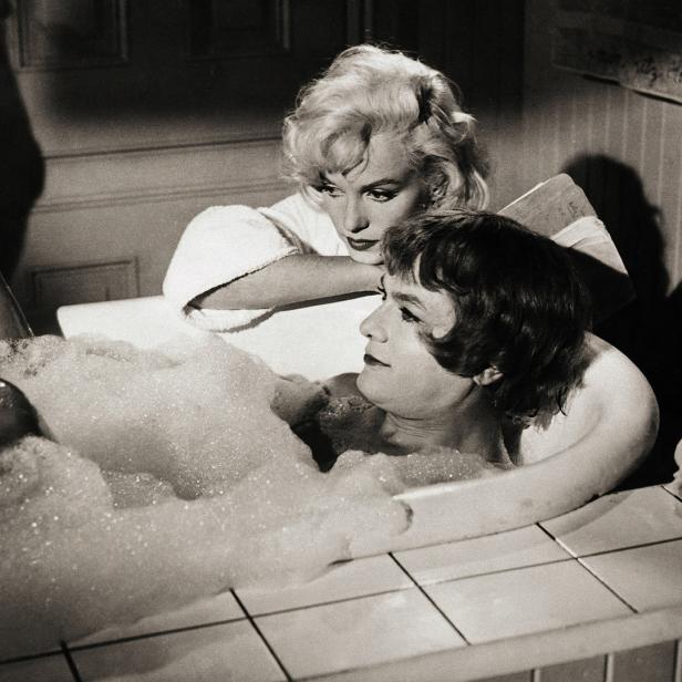 Marilyn Monroe schaut zu, wie eine Frau in einer mit Schaum gefüllten Badewanne liegt.