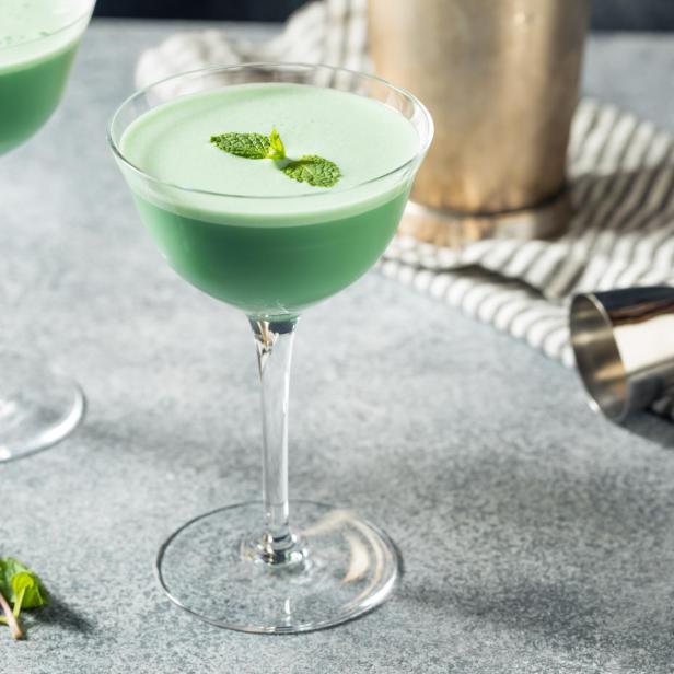 Zwei Grasshopper-Cocktails, garniert mit Minze, auf einem Tisch.
