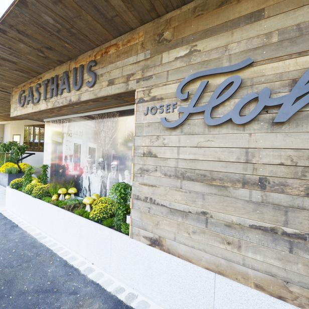 Das Gasthaus Josef Floh mit Holzfassade und dekorativer Bepflanzung im Außenbereich.