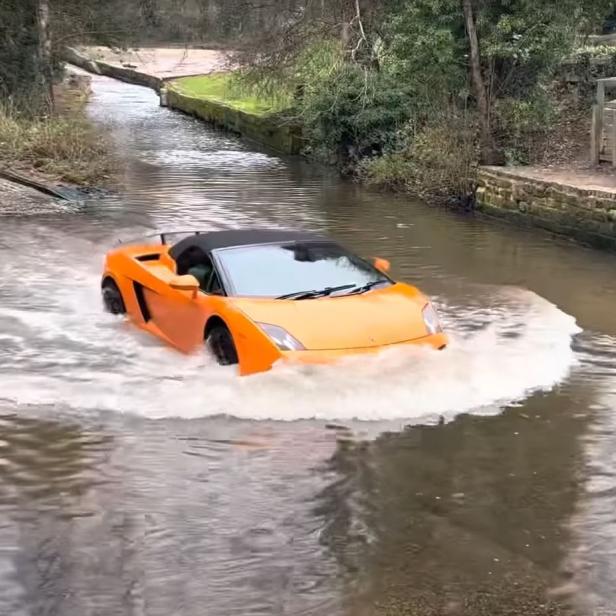 Ein orangefarbener Lamborghini fährt durch einen überfluteten Fluss.