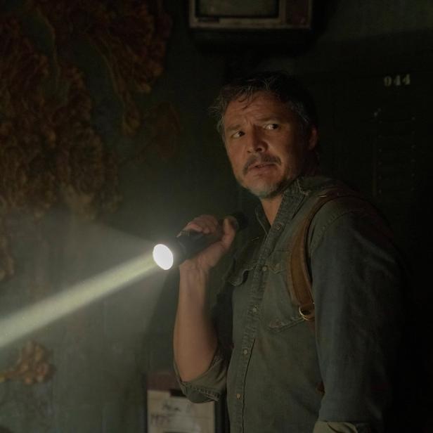 Pedro Pascal als Joel in einer dunklen Szene aus „The Last of Us“, mit einer Taschenlampe in der Hand.