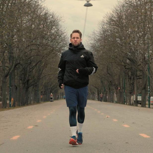 Ein Mann joggt auf einer Allee mit kahlen Bäumen.