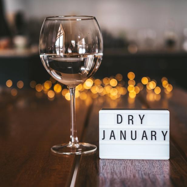 Ein Glas Wasser steht neben einer Leuchtreklame mit der Aufschrift „Dry January“.