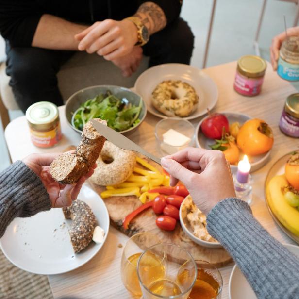 Ein Tisch mit belegten Bagels, Obst, Gemüse und Getränken für ein gemütliches Beisammensein.