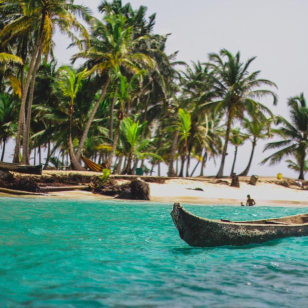 Ein traditionelles Holzboot schwimmt vor einem tropischen Strand in Panama.